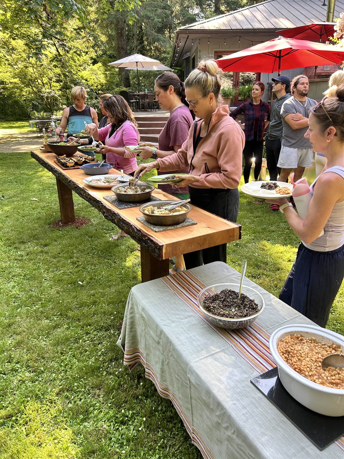 Guests serving themselves lunch from a live-edge wooden buffet table on the lawn
